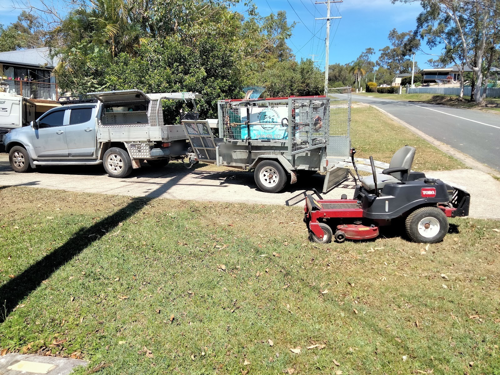 Shane's ute and trailer with a red ride-on mower on a freshly mown verge