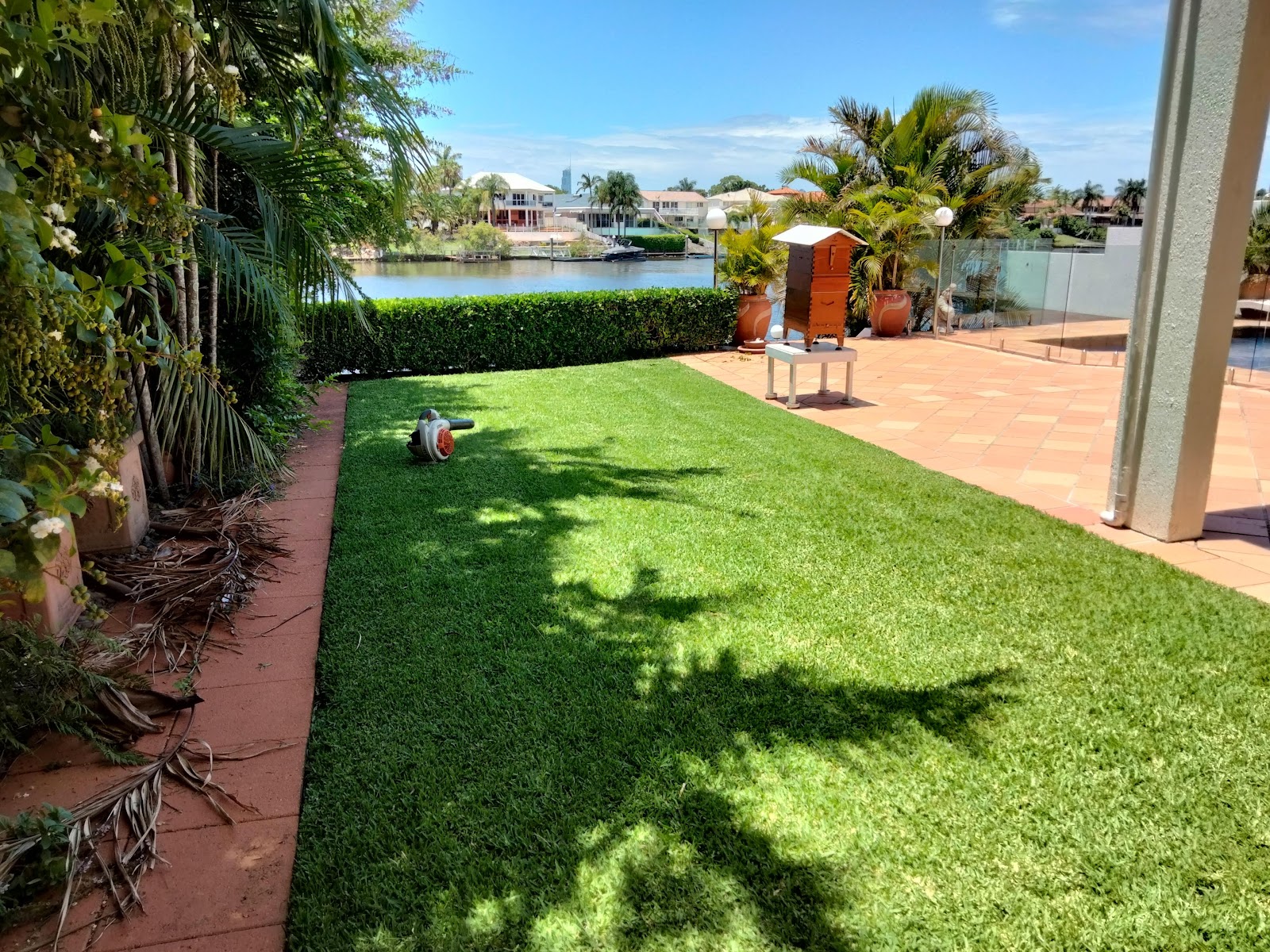 Striped waterfront lawn next to a pool terrace with the canal behind